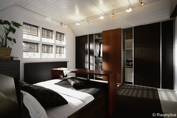 Modernes Schlafzimmer mit großem begehbarem Kleiderschrank, stilvollen Möbeln und Tageslicht.